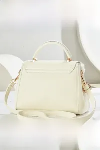 Detail view of cream white leather crossbody bag with lychee texture and side pompom