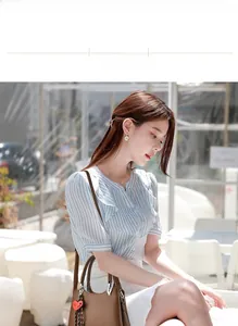 Brown lychee texture handbag with heart charm shown on model in striped shirt