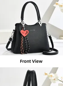 Front view of black pebble leather handbag with twin handles and heart charm accessory