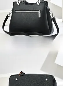 Detail of black pebbled leather handbag featuring back zipper and protective base studs