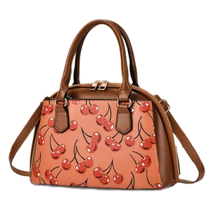 Chic cherry print crossbody shell bag with brown leather handles and pink finish