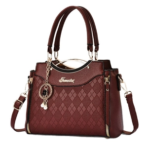 Elegant deep red textured leather handbag with quilted pattern and pearl charm accessory