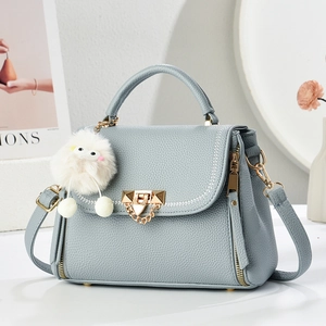 Gray-blue leather handbag with gold twist lock and white plush pompom charm