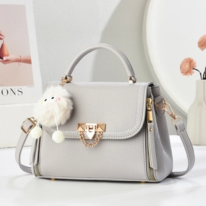 Elegant grey pebble leather satchel bag with gold lock and plush monster charm decoration