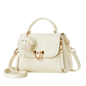 Elegant cream leather crossbody bag with gold hardware and plush monster charm