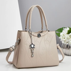 Borsa beige con goffratura a cuore e ciondolo floreale su sfondo minimalista