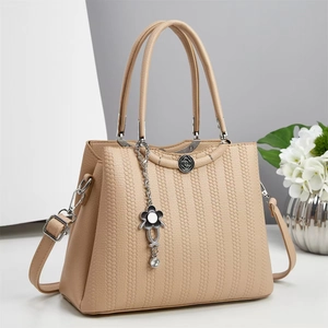 Beige large capacity tote bag with honeycomb texture and floral pendant in studio setting