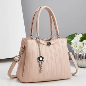 Pink faux leather crossbody handbag with flower charm and round black hardware