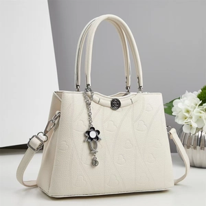 Dettaglio borsa beige con motivi a cuore goffrati e ciondoli a forma di fiore
