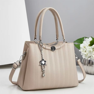 Detail view of beige handbag showing honeycomb texture and floral charm accessory