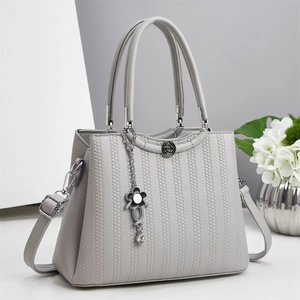 Detail of light gray crossbody bag with honeycomb texture and floral chain pendant