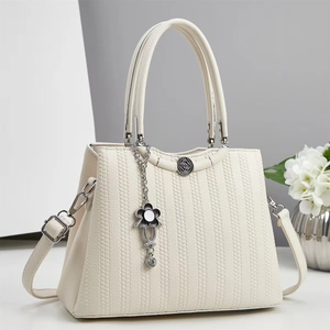Close-up of ivory handbag with honeycomb embossed texture and flower metal charm