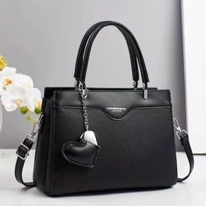 Close-up of black lychee leather handbag with heart pendant and detachable strap