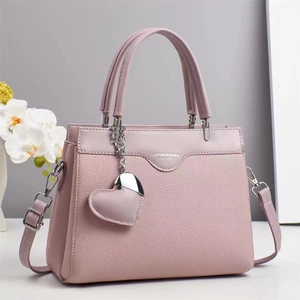 Close-up of light pink lychee texture handbag with heart pendant and leather stamping