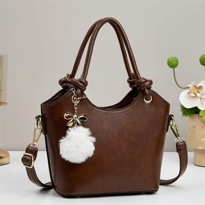Elegant brown PU leather bucket bag with knotted handles and a white fluffy pompom charm
