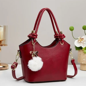 Burgundy PU leather bucket bag with double handles and plush charm in a lifestyle setting
