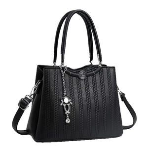 Classic black textured leather tote bag with elegant floral charm and top handles