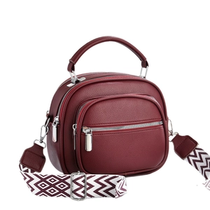 Burgundy faux leather top handle bag with multi-zipper layers and geometric wide strap