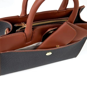 Detail of two-tone tote bag with brown leather handles and grey mesh texture fabric
