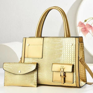 Detail shot of golden crocodile embossed tote bag set with matching wallet and chain