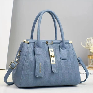Dettaglio della borsa tote blu in pelle martellata con hardware dorato e righe a rilievo