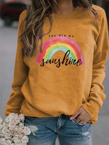 Detail of sunshine rainbow print on ginger yellow long sleeve sweatshirt with crew neck