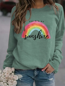 Detail view of the colorful watercolor rainbow print and slogan on this green sweatshirt