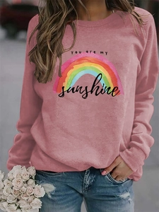 Close-up of rainbow print and 'You are my sunshine' text on rose pink sweatshirt