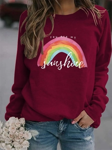 Detail of burgundy sweatshirt featuring rainbow print and You are my sunshine text