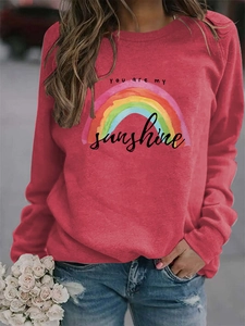 Close-up of rainbow print and You Are My Sunshine lettering on pink long sleeve sweatshirt