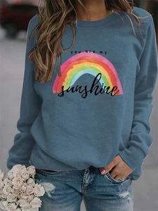 Close-up of rainbow print and 'you are my sunshine' text on blue long sleeve sweatshirt
