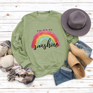 Flat lay of green sweatshirt with rainbow print and 'you are my sunshine' text