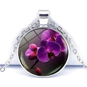 Détail d'un collier argenté avec pendentif rond en verre orné d'un motif d'orchidée violette