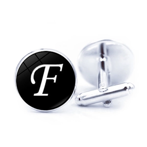 Detailed view of silver metal cufflinks with black round inlay and white script letter F
