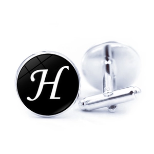 Close-up of silver metal cufflinks with a black round face featuring white letter H