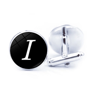 Macro shot of silver metal cufflinks with letter I design on black glass surface