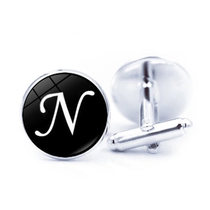 Macro shot of silver metal cufflinks with white letter N on black dial and glass coating