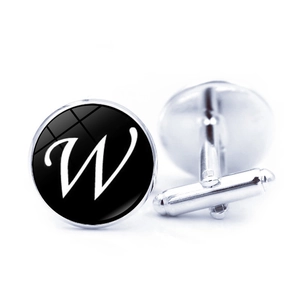 Close-up of silver-tone round cufflinks with black base and white cursive letter W
