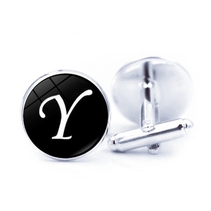 Close-up of polished silver cufflinks with white letter Y on a sleek black background