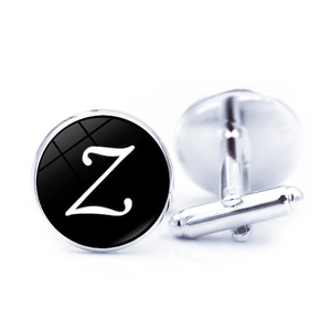Macro shot of silver metal cufflinks with black round inlay featuring a white letter Z