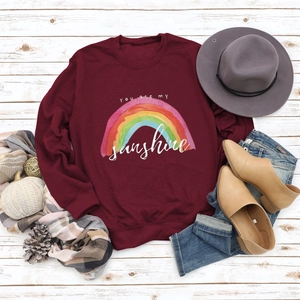 Flat lay of burgundy rainbow sweatshirt with YOU are my sunshine print and autumn accessories