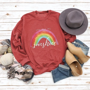 Flat lay of red sweatshirt with You are my sunshine rainbow print and autumn accessories