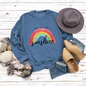 Flat lay of navy crewneck sweatshirt with rainbow sunshine print and autumn accessories