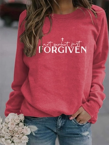Detail shot of 'Not Perfect Just Forgiven' text and cross on a red long sleeve sweatshirt