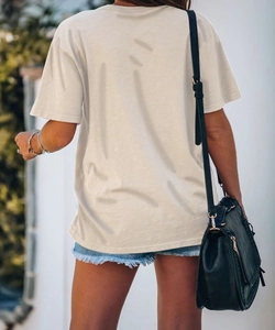 Vista posteriore di una t-shirt girocollo bianco crema ampia abbinata a pantaloncini di jeans