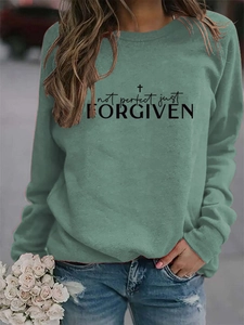 Close-up of the black 'not perfect just FORGIVEN' print on a sage green sweatshirt