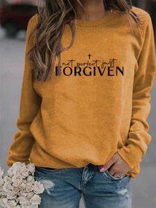 Close-up of ginger yellow crewneck sweatshirt with Not Perfect Just Forgiven printed text