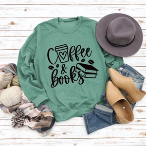 Détail d'un sweat vert forêt Coffee & Books avec accessoires d'automne sur fond de bois