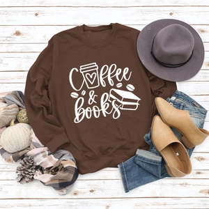 Vue à plat du sweat Coffee & Books marron avec accessoires sur fond bois blanc