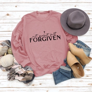 Flat lay of pink sweatshirt with Not Perfect Just Forgiven text and autumn accessories